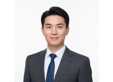 A professional studio-quality passport-sized photo of a male cabin crew candidate. The shot is framed from the collarbone to the top of the head. He looks directly at the camera with a polite, natural closed-mouth smile. His hair is neatly combed and tidy, revealing his ears. He is clean-shaven. He wears a crisp white dress shirt and a dark blue tie under a closed, dark grey suit jacket. The background is a plain white, with soft, diffused studio lighting and no harsh shadows. No accessories or alterations.