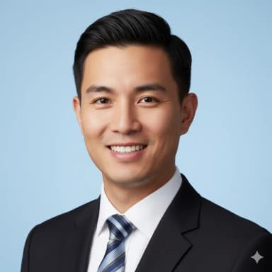 Studio-quality close-up portrait of a male cabin crew candidate, framed from the collarbone to the top of his head. He displays a warm, genuine open-mouth smile. His hair is perfectly styled, short, and tidy. He is clean-shaven. He is wearing a dark, professional fitted suit jacket over a white shirt and a patterned tie. The photo features a plain light blue background, is sharp, in focus, and lit naturally without harsh glare.